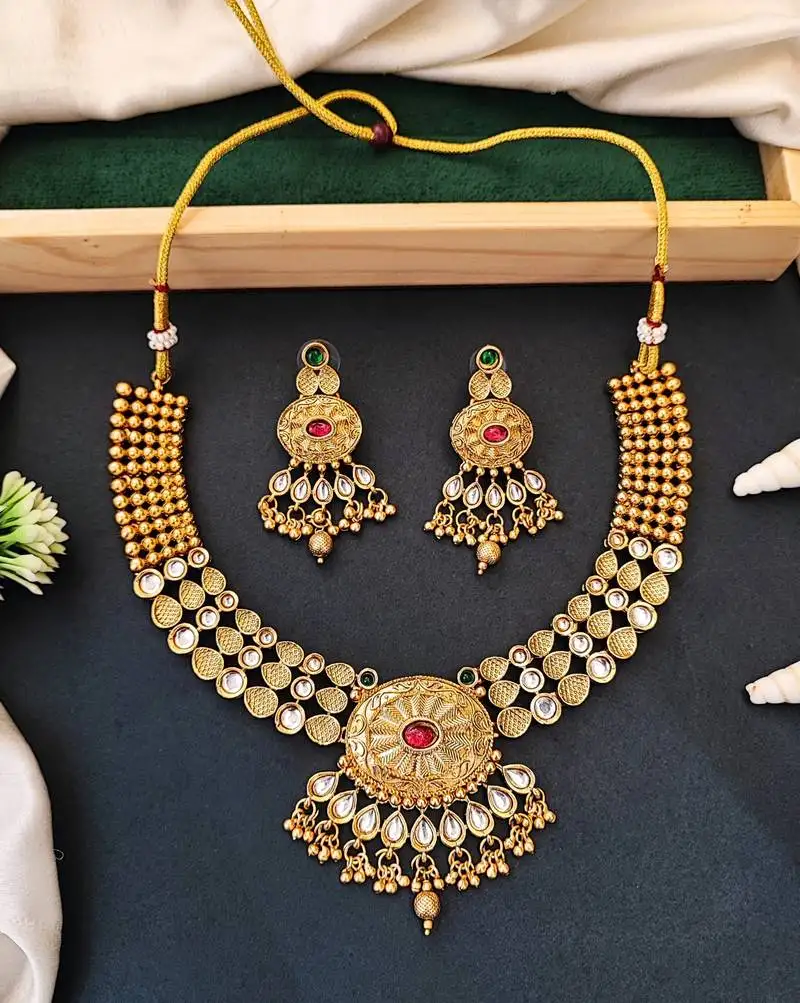 Beautiful gold-plated kundan necklace and earrings set with red and green stones, pearl accents for her