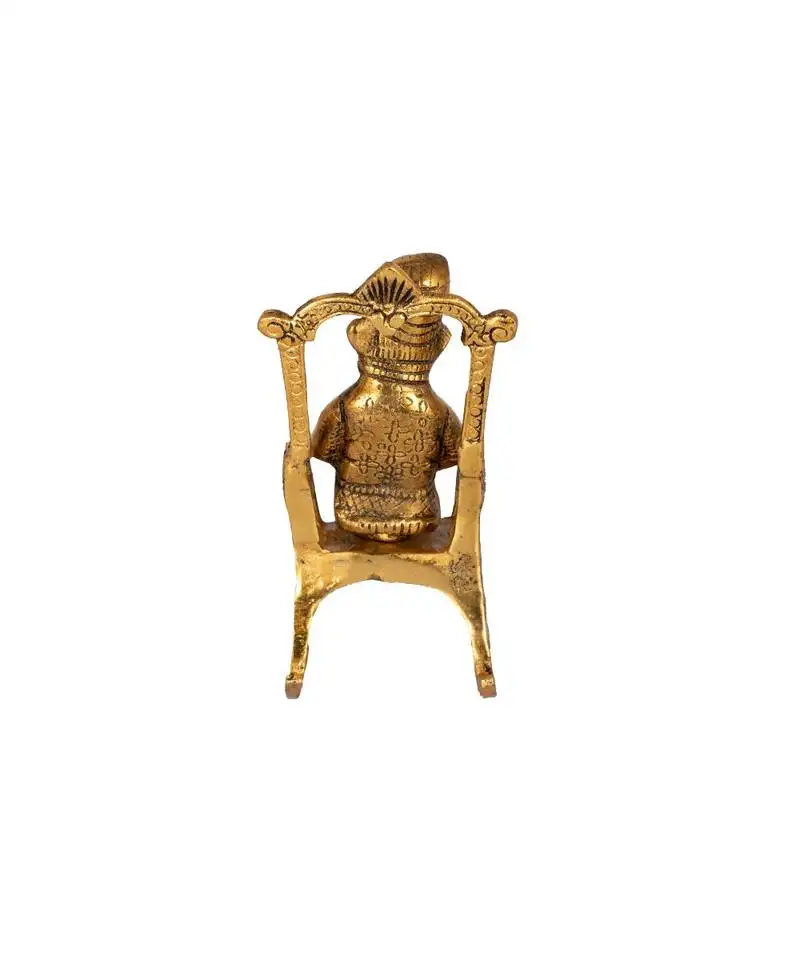 Lord ganesha statue sitting on a chair and reading ramayan