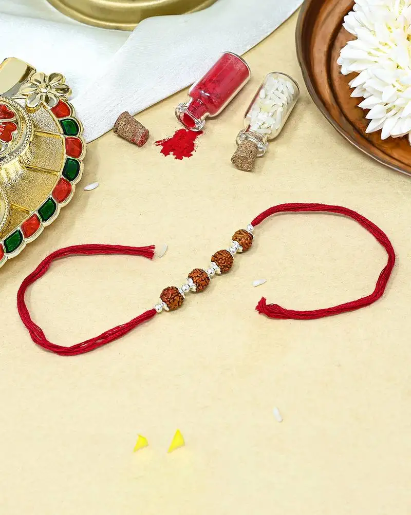 Red thread rakhi with four rudraksha beads and silver detailing